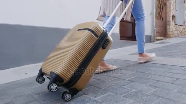 Travel through Europe. A woman carries a bag on wheels on the narrow street of the old town. Only the legs and a bag visible in the frame — Stock Video