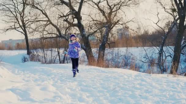 Смішна дівчина щасливо біжить на снігу, щасливий початок зими — стокове відео