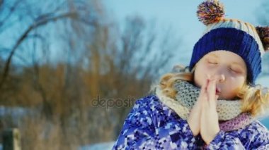 Neşeli kız 5 yıl kış portresi. Kameraya sıcak avuç içi görünüyor