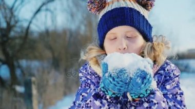 Ellerinde karda üfleme neşeli küçük kız portresi. Kış, olumlu duygular varış sevinir