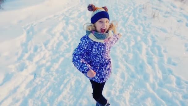 Dziewczynka 5 lat stary baw się dobrze działa na śniegu, Śmieszne miny, śmiejąc się — Wideo stockowe