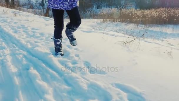 Счастливому ребенку весело бегать по свежему снегу. Смеющиеся счастливо, позитивные эмоции. Прекрасное вечернее освещение — стоковое видео