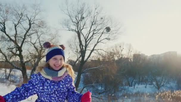 Радостная зима. Веселая маленькая девочка бежит по снегу, смеясь — стоковое видео