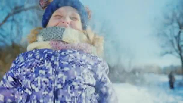 Зимнее веселье. Портрет девушки, которая бросает снег и смеется — стоковое видео