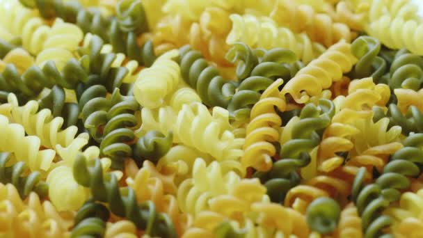 Uncooked pasta in the form of spiral of different colors — Stock Video