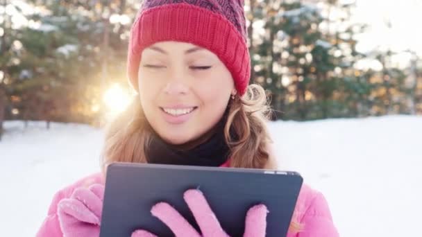 Привлекательная молодая женщина наслаждается планшетом или в снежном лесном парке — стоковое видео