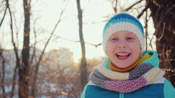 Meisje maakt vijf jaar een grappige gezicht, de camera kijken, lachen. Winter vreugde en plezier — Stockvideo