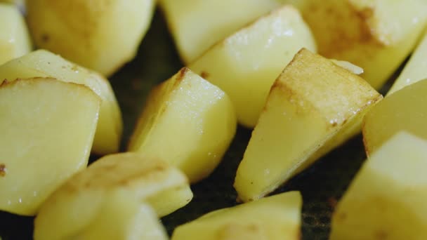 Lätt friterad potatis blandat i en stekpanna. God, men inte hälsosam mat — Stockvideo