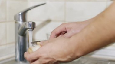 Adam yıkar ve mantar mutfak temizler. Resimde, yalnızca kollarını görülür