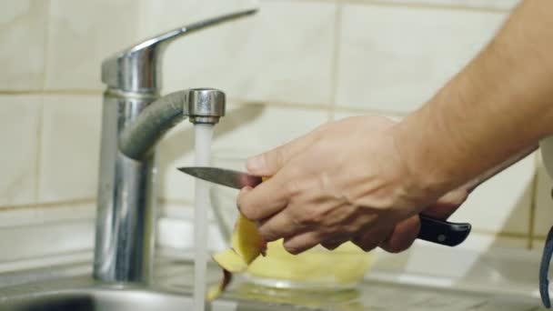 El hombre limpia papas en la cocina. Lavar, pelar y cortar — Vídeos de Stock