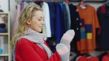 Kırmızı kazaklı çekici kadın sıcak mittens çalışır. Bir giyim mağazasında olması gerektiği