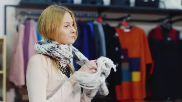 Mujer atractiva probándose una modelo se ve bufanda caliente en una tienda de ropa. Compras alegres — Vídeos de Stock