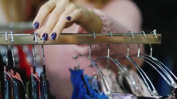 A escolha da roupa interior. Mão feminina com manicure toca um cabide para roupas com roupa interior — Vídeo de Stock