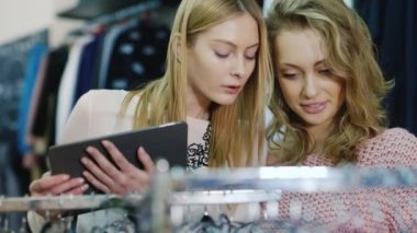 Tablet ile alışveriş. İki kadın bir giyim mağazası şeylere bak, Tabletinizi kullanın
