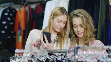 Smartphone ile alışveriş. İki kadın bir giyim mağazası, kullanım telefon her şey görünüyor
