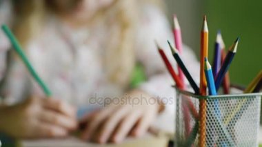 Çocuk berabere, sığ derinlik-in tarla. Ön planda, bir vazo ile renkli kalemler, çocuk ellerini çizmek