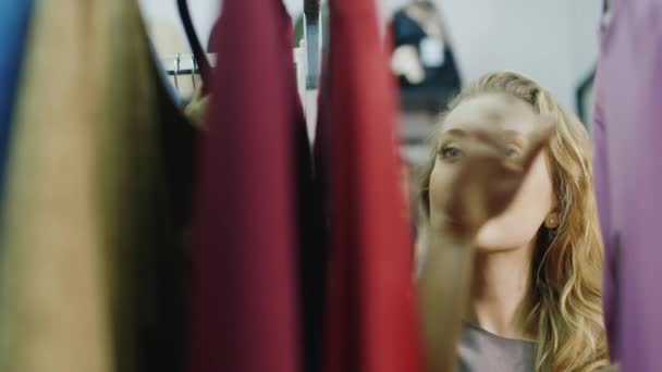 Portrait d'une jeune femme choisit des choses dans le magasin de vêtements pour femmes — Video