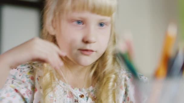Πορτρέτο του ξανθού κοριτσιού επιλέγει χρωματιστό μολύβι ένα βάζο. Ρηχό βάθος πεδίου — Αρχείο Βίντεο