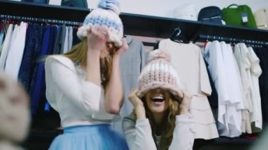 Eğlenceli mağaza iki genç güzel kadın. Gülüyor, olumlu duygular şapka üzerinde deneyin