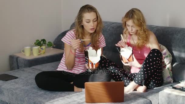 Friends eating fast food at home, watching a movie on a laptop. Pajama party two young women — Stock Video