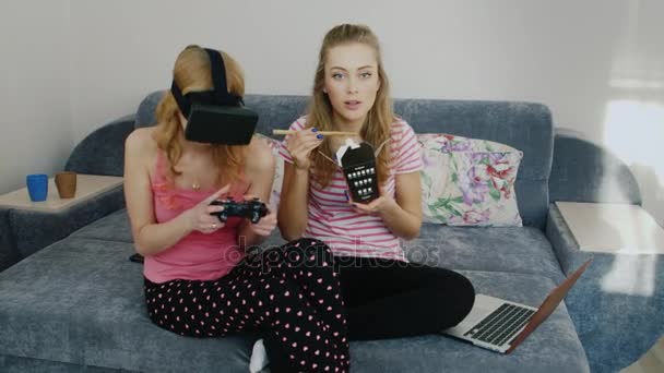 Dois podurgi casa divertida. Jogando em capacete realidade virtual, comer comida e assistir televisão. Pajama festa namoradas — Vídeo de Stock