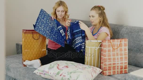 Depois de uma compra bem sucedida. Duas mulheres a olhar para as suas compras, sentadas na cama do quarto. Em torno de um monte de sacos de compras — Vídeo de Stock