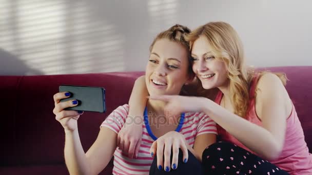 Twee jonge vrouwen praten op de videochat. Positieve emoties, zwaaien hun handen in de telefooncamera — Stockvideo