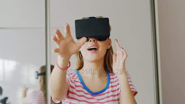 Young woman wearing a helmet virtual reality at home. Catches hands objects in the air, laughing, gets pleasure — Stock Video