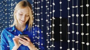 Tipik bir haber smartphone cep telefonu ile bir gece kulübünde tatlı genç bir kadın. Güzel mavi gözlü mavi gömlekli shes