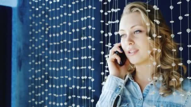 Młoda kobieta rozmawia przez telefon w klubie. Stałego o dekoracji koraliki szklane — Wideo stockowe