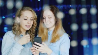 İki genç kadın arkadaş bir gece kulübünde smartphone cep telefonu ile mesaj okuma