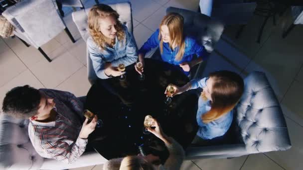 Группа молодых людей отдыхает за столом в кафе или ресторане, пьет вино, болтает. вид сверху — стоковое видео