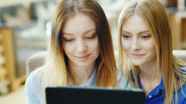Två unga attraktiva kvinnor njuter tablett. Sitta på ett café på en solig eftermiddag, porträtt — Stockvideo