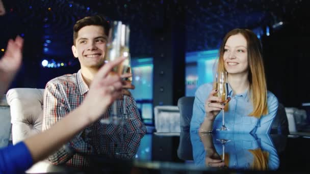 Группа молодых людей отдыхает в ресторане, звонят в стаканы — стоковое видео