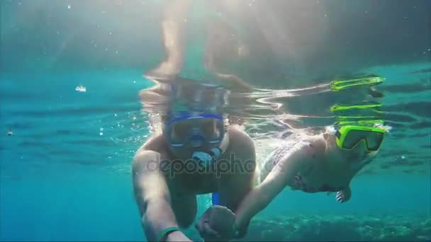 Um jovem casal está filmando um vídeo selfie sob a água. Nade no mar com uma máscara e tubos — Vídeo de Stock