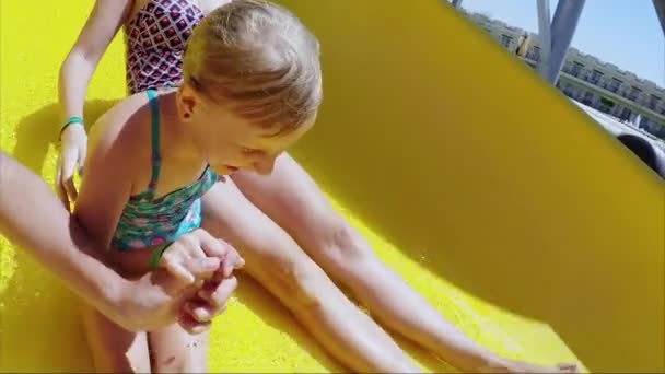 Mãe e filha estão montando um escorrega de água no parque aquático. Diversão, a menina ri, emoções positivas, grande descanso — Vídeo de Stock