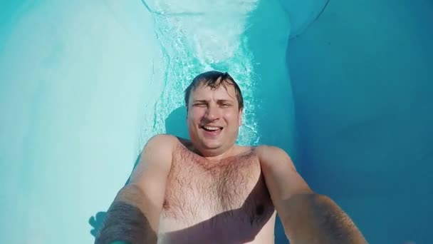 Un jeune homme amusant est monté sur un toboggan dans un parc aquatique. Gouttes dans l'eau avec beaucoup d'éclaboussures, vidéo POV — Video