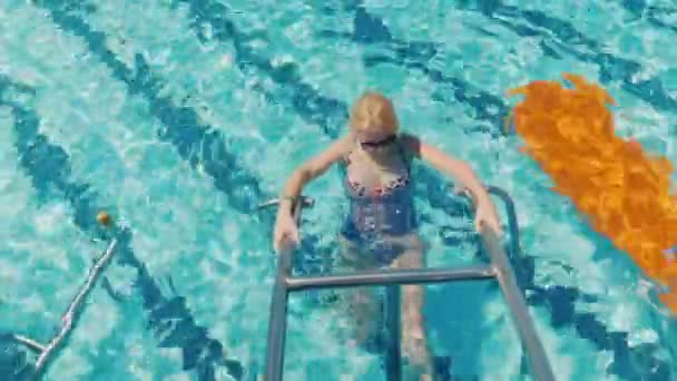 Eine junge Frau im Badeanzug trainiert diesen speziellen Simulator im Pool. Wassergymnastik und Sport, ein gesunder Lebensstil — Stockvideo