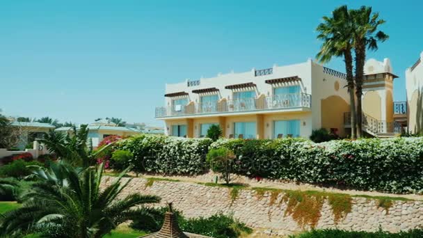 Sharm el Sheikh, Egito, março de 2017: Edifícios de um resort de luxo. Nas proximidades crescem palmeiras e muitos arbustos floridos. Tiro Pan — Vídeo de Stock