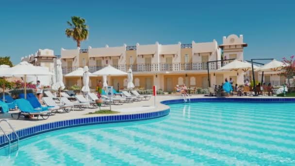 Sharm el Sheikh, Egypt, March, 2017: Typical for Egypt, a luxury hotel with a pool and a bar near the water. Sun beds tanning, umbrellas from the sun - tourists are resting — Stock Video