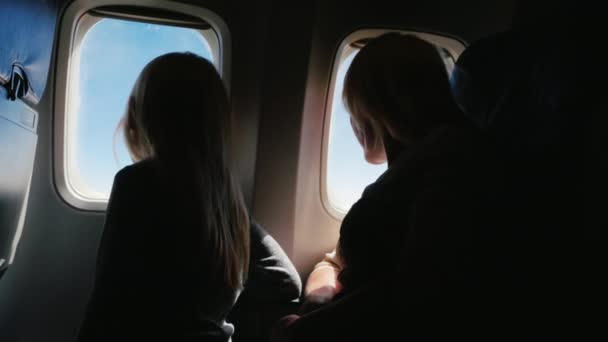 両親と旅行を一緒に喜ぶ。ママと娘は、6 年間、飛行機の窓を見ています。今後の休暇を楽しみにして — ストック動画