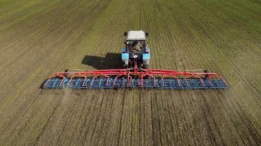 Arkadan Görünüm - traktör bahar alanında toprak yetiştirerek. Güneşli bir gün, mavi bulutlar ile ilgili değil