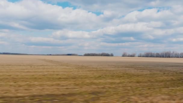 Blick aus dem Fenster eines schnell fahrenden Autos. Feld Anfang Frühling - gepflügtes Land und blauer Himmel mit Wolken. Ackerland. pov 3-Achsen-stabilisiertes Video — Stockvideo