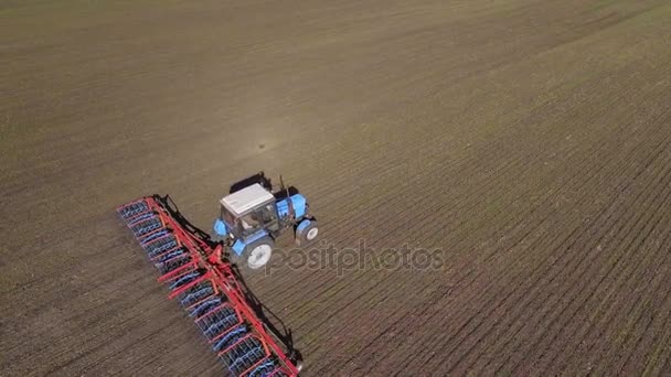 Een trekker met een harrow ploeg reist door het veld in het vroege voorjaar. Het frame diagonaal, kruist luchtfoto video — Stockvideo