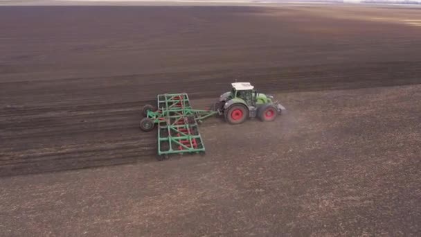 Трактор рисует сельскохозяйственное устройство для боронования земли. Весенние работы в поле, аэрофотосъемка — стоковое видео
