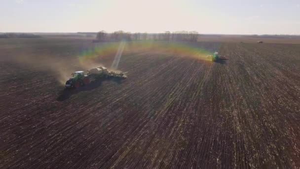 Dwa ciągniki zasiać pola na wiosnę. Fotografowania przed podkreśla zachód słońca, piękny i efekt tęczy — Wideo stockowe