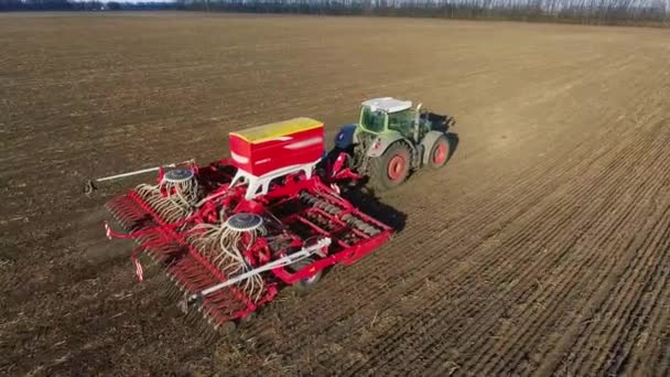 Ciągnik ciągnie duży siewnik na polu. Siewów wczesną wiosną, wiejski krajobraz. Koncepcja - nowoczesnego agrobiznesu — Wideo stockowe