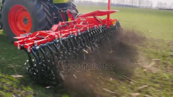 A rapidly moving part of the earth-harrowing machine. Harrowing of the land in early spring. The camera follows the mechanism - steadicam shot — Stock Video