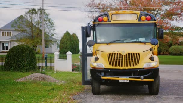 Wilson, NY, EUA - OKT, 2016: Limusina de ônibus amarela no fundo de uma típica casa americana. De pé no pátio, à espera dos passageiros — Vídeo de Stock