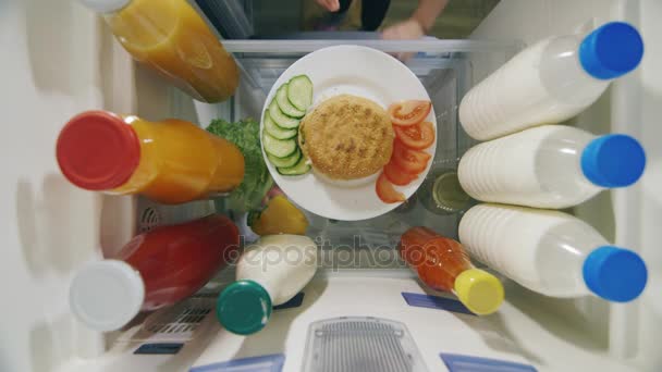 Un niño gracioso come una hamburguesa dentro del refrigerador. Vista desde arriba, cara irreconocible — Vídeos de Stock